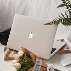 a white laptop sitting on top of a table next to flowers