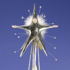 a silver and white star shaped decoration on top of a pole with snow flakes