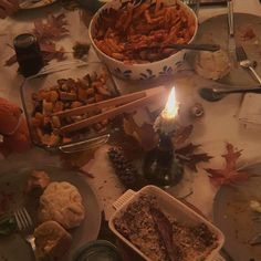 a table full of food with a lit candle in the middle and other dishes on it