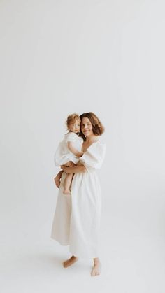 a woman holding a baby in her arms while standing against a white background with the words,