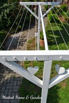 a white wooden bench with hearts on the bottom and back legs, sitting in front of a house