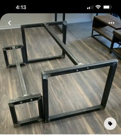 three metal frames sitting on top of a hard wood floor next to a wooden table