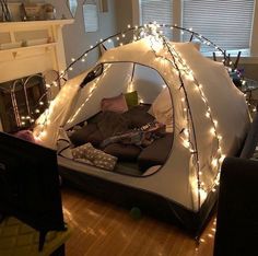 a tent that has been set up in the living room with christmas lights on it