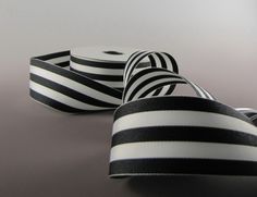 three rolls of black and white striped ribbon on a gray surface with one roll in the foreground