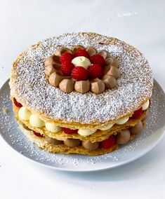 a white plate topped with a cake covered in powdered sugar and raspberries