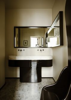 a bathroom with two sinks and a mirror above it in the middle of the room