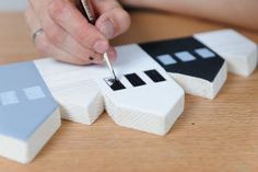 a person is using a pen to write something on wood blocks that are shaped like houses