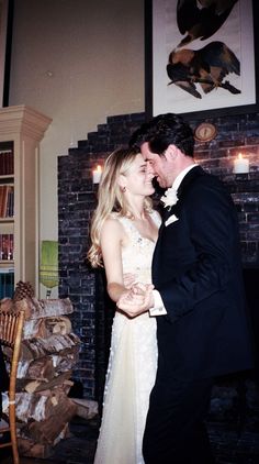 a bride and groom dance together in front of a fire place at their wedding reception