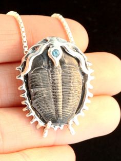 "This unique Trilobite Fossil Pendant is 1 3/8\" long and 1 1/8\" (35 x 28.5 mm) across and cast in sterling silver. A 3 mm gem is set in the center hood of the Trilobite. Each of the pendants will be slightly different due to subtle variations between each fossil specimen but all are uniquely beautiful. There are over 20,000 trilobite species and the fossils are found on every continent on earth. They existed 300 million years ago and are extinct arthropods, a distant relative to horseshoe crab Fossil Art, Dinosaur Jewelry, Bug Jewelry, Jewelry Ocean, Trilobite Fossil, Fossil Jewelry, Insect Jewelry, Ocean Jewelry, Funky Jewelry