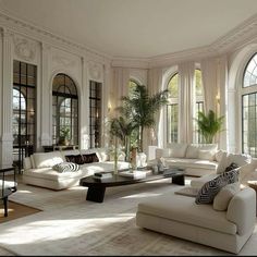 a large living room with white couches and lots of windows on the side wall