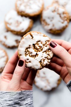 a person holding a frosted donut in their hand