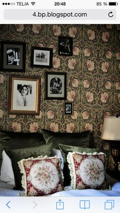 an image of a bedroom setting with pictures on the wall and pillows in front of it