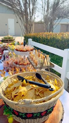 a table filled with lots of food sitting on top of a wooden table next to a white fence