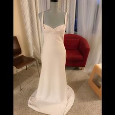 a white wedding dress on display in front of a red chair