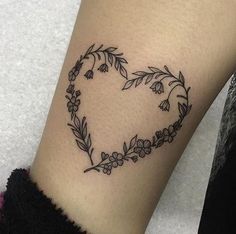 a woman's arm with a heart shaped flower tattoo on the left side of her leg