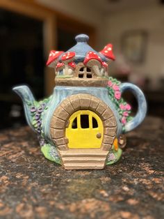 a teapot shaped like a house with a yellow door