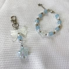 two bracelets with beads and charms on a white cloth covered tablecloth, one has a star charm attached to it