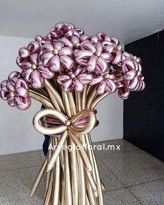 a gold vase filled with pink flowers on top of a tiled floor