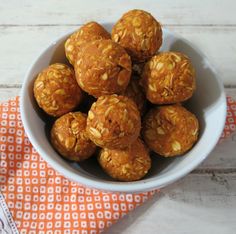 a bowl filled with peanut butter balls on top of an orange and white cloth next to a measuring cup