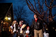 a man and two children are standing in front of christmas lights