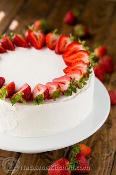 a white cake topped with fresh strawberries on top of a wooden table