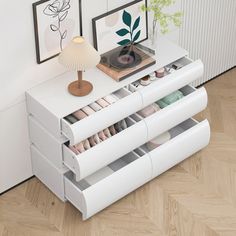 a white dresser with drawers and pictures on the wall