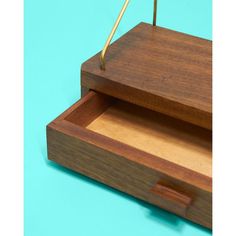 a wooden box with two drawers and a pen sticking out of the top, on a blue background