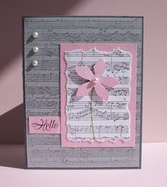 a close up of a card with music sheets and a pink flower on the front