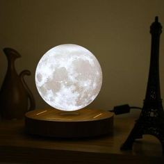 the moon lamp is on top of a wooden stand