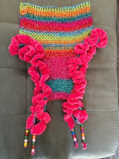 a crocheted bag with pom poms on it sitting on a couch