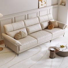 a living room with a white couch and two pillows on the floor next to a coffee table