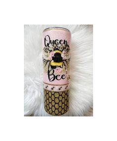 a pink and black cup with the words queen bee on it sitting on a white rug