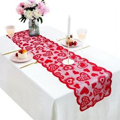 the table is decorated with red hearts on it and pink flowers are in vases