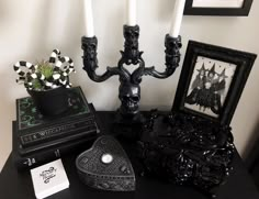 a black table topped with two candles and other decorative items next to a framed picture