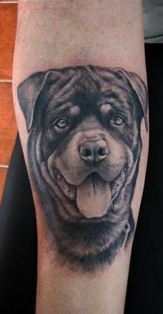 a black and grey dog tattoo on the leg, with his tongue hanging out to show it's teeth