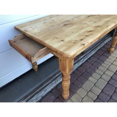 a wooden table sitting on top of a brick walkway next to a white wall and door