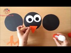 someone is making a paper bird craft with black circles and white dots on the face