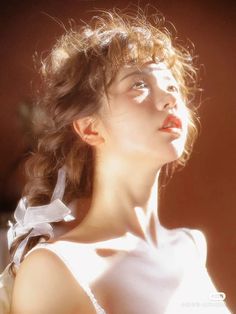 a woman with her hair blowing in the wind, wearing a white dress and red lipstick