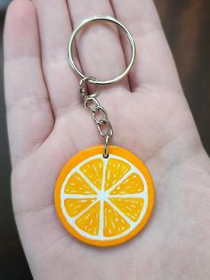 a hand holding an orange slice keychain in it's palm