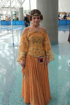 a woman in an orange dress is posing for the camera