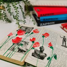 an open book sitting on top of a table next to flowers and bookshelves