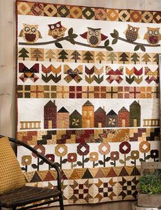 an owl themed quilt hangs on the wall next to a chair and potted plant