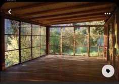 an empty room with wooden floors and large windows on the wall, overlooking trees in the distance