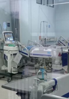 an operating room with medical equipment in the foreground and on the far wall is a large mirror