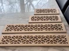 three wooden coasters sitting on top of a marble counter next to a window with trees in the background