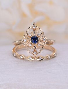 a gold ring with a blue stone in the center and white diamonds around it, sitting on top of a table