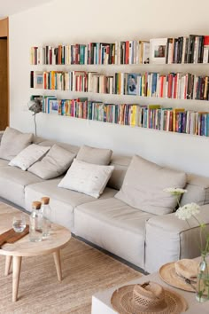 a living room filled with furniture and lots of books on the shelves above it's headboard