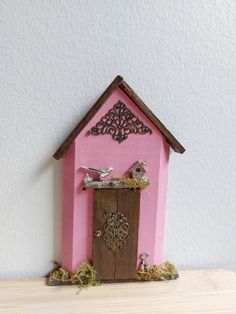 a pink birdhouse with two birds perched on the roof and one in the door