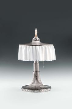 a silver table lamp with a white cloth on it