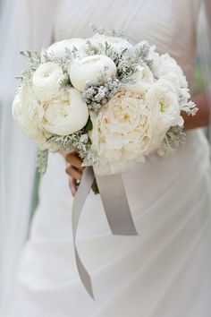 a bride holding a bouquet of white flowers